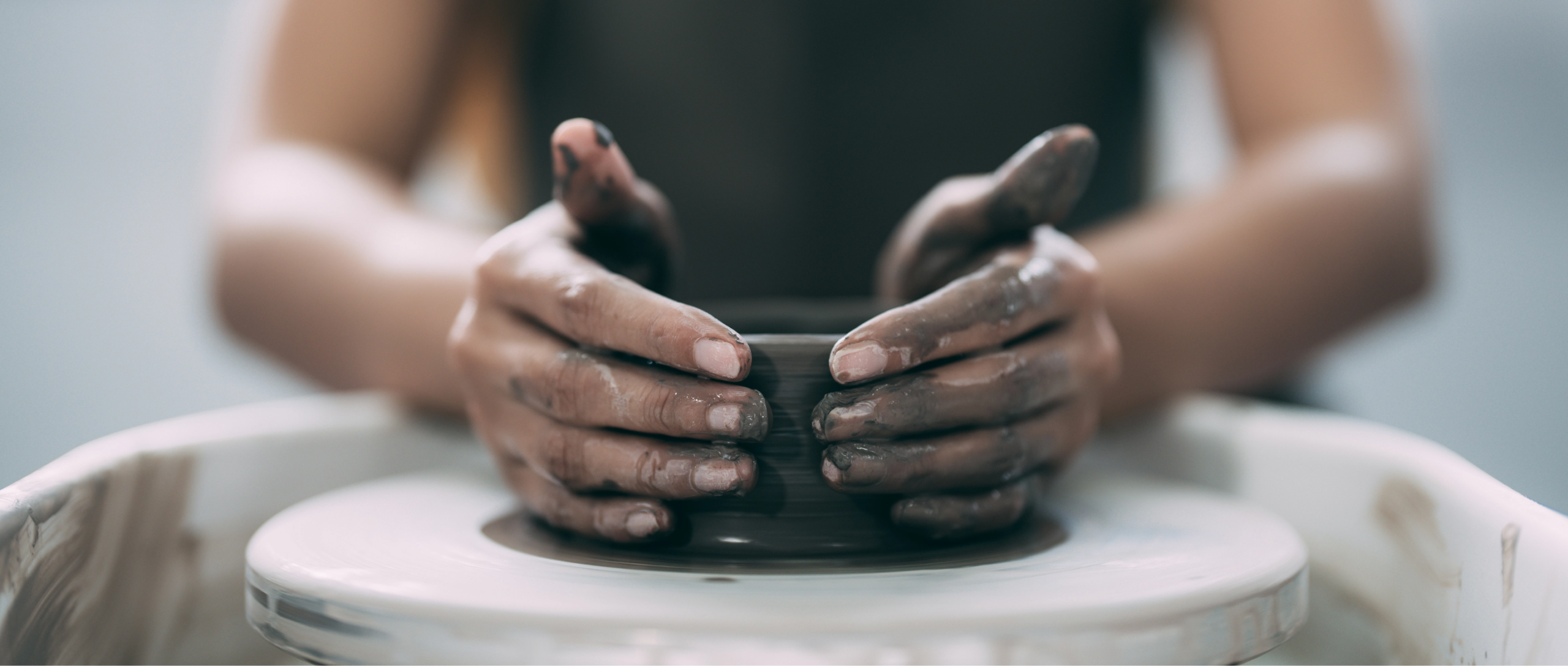 inquadratura di un paio di mani che modella dell'argilla sul tornio